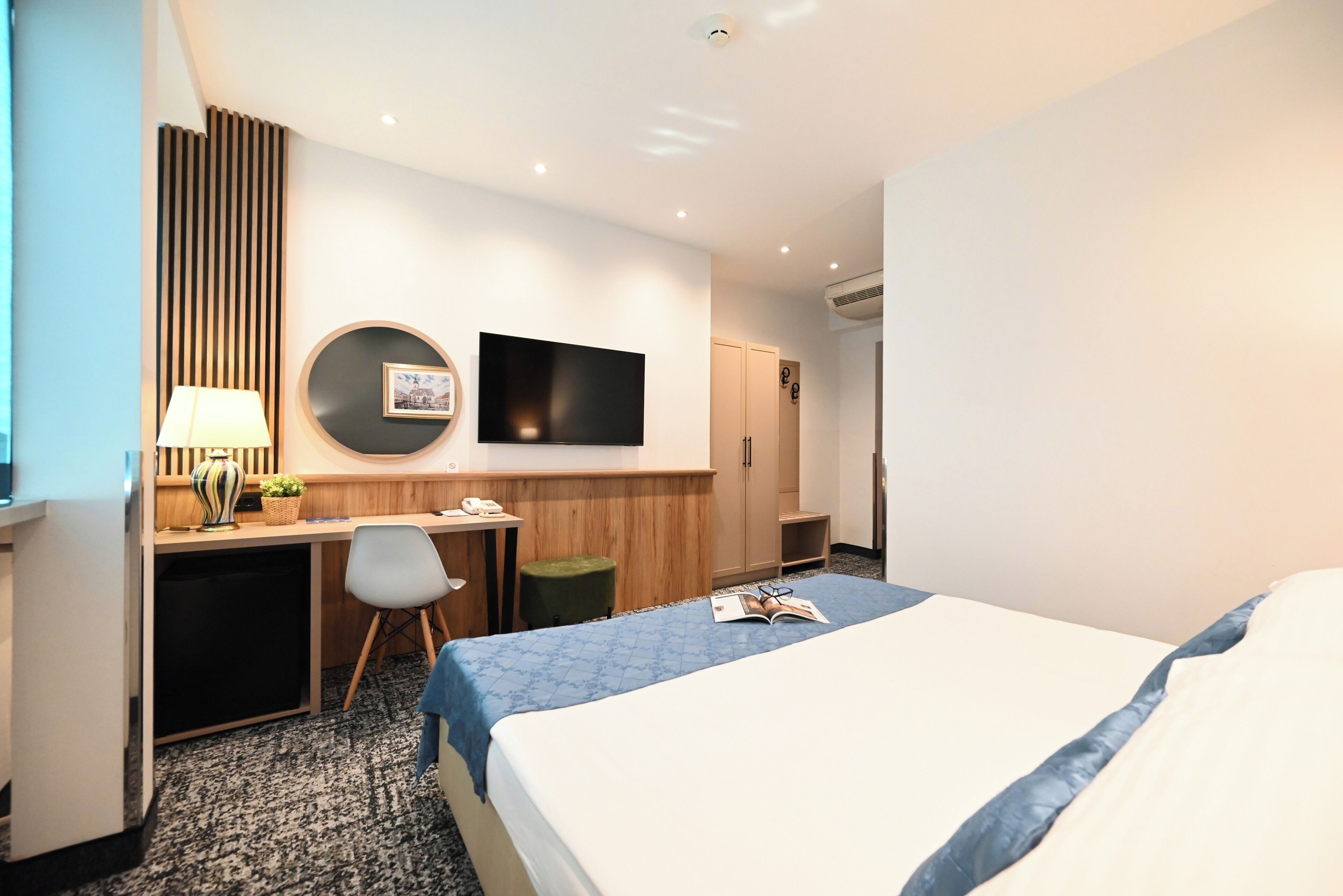 A hotel room with a bed, desk, chair, TV, and wardrobe.