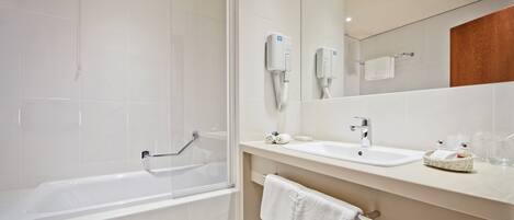 Un baño moderno con una bañera, un lavabo, un espejo y un perchero para toallas.