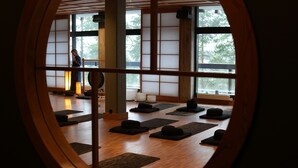 Una habitación japonesa tradicional con esteras de tatami, un celosía de papel y una persona practicando yoga.