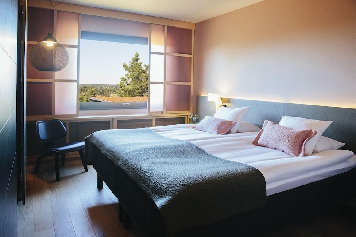 A hotel room with a large bed, a desk, and a view of the outdoors.