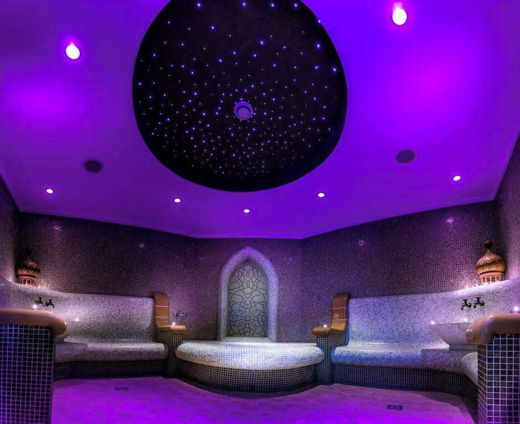 A room with a starry ceiling, a patterned wall, and a seating area with a central niche.