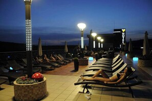 A rooftop lounge area with sun loungers, a pool, and a sign for a hotel. - Business V Hotel (Tirgu Mures)