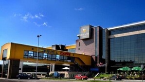 A modern building with a yellow facade and a large glass entrance. - Business V Hotel (Tirgu Mures)