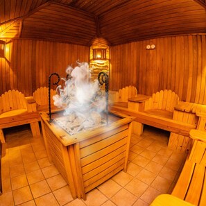 A sauna with wooden benches and a central steam feature. - Business V Hotel (Tirgu Mures)