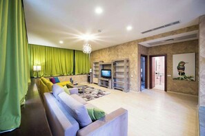 A living room with a sofa, a television, and a green curtain. - Business V Hotel (Tirgu Mures)