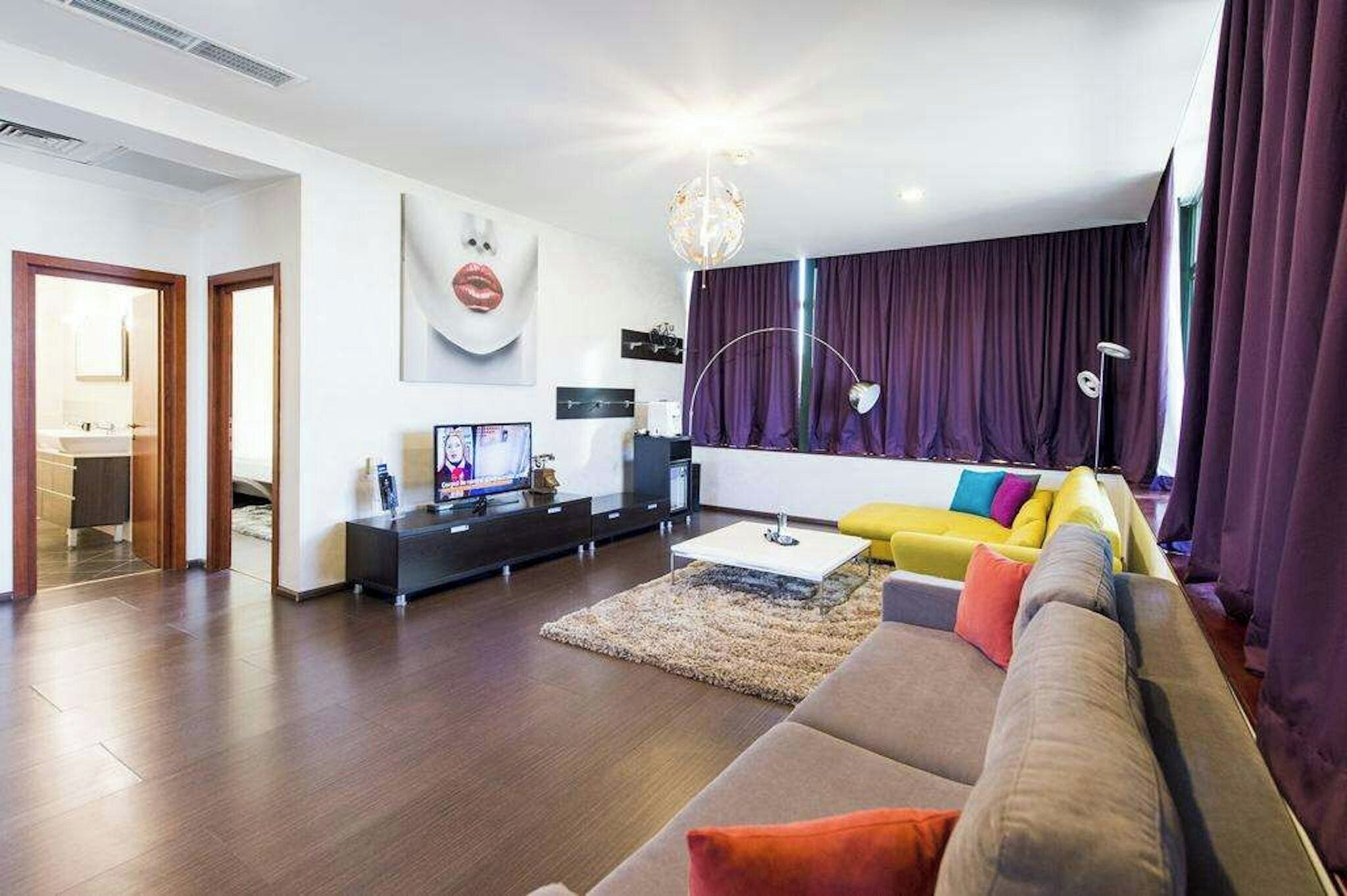 A modern living room with a sofa, a television, and a dining area.