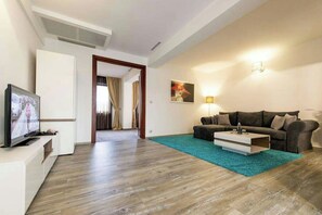 Un salon moderne avec un téléviseur à écran plat, un canapé, une table basse et un tapis de couleur turquoise.