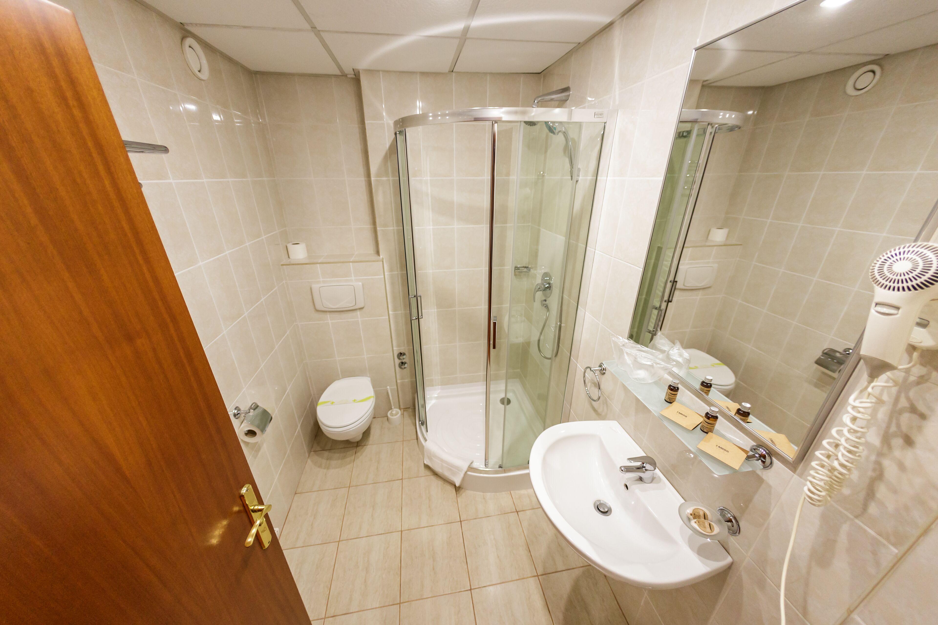 A modern bathroom with a glass-enclosed shower, a white sink, and a toilet.
