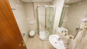 Une salle de bain moderne avec une douche à parois de verre, un lavabo blanc et des toilettes.