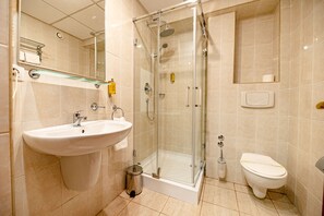 A modern bathroom with a glass-enclosed shower, a white sink, and a toilet.