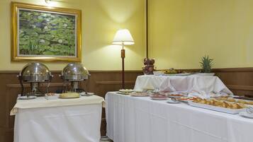 A buffet setup with various food items and a decorative painting on the wall.