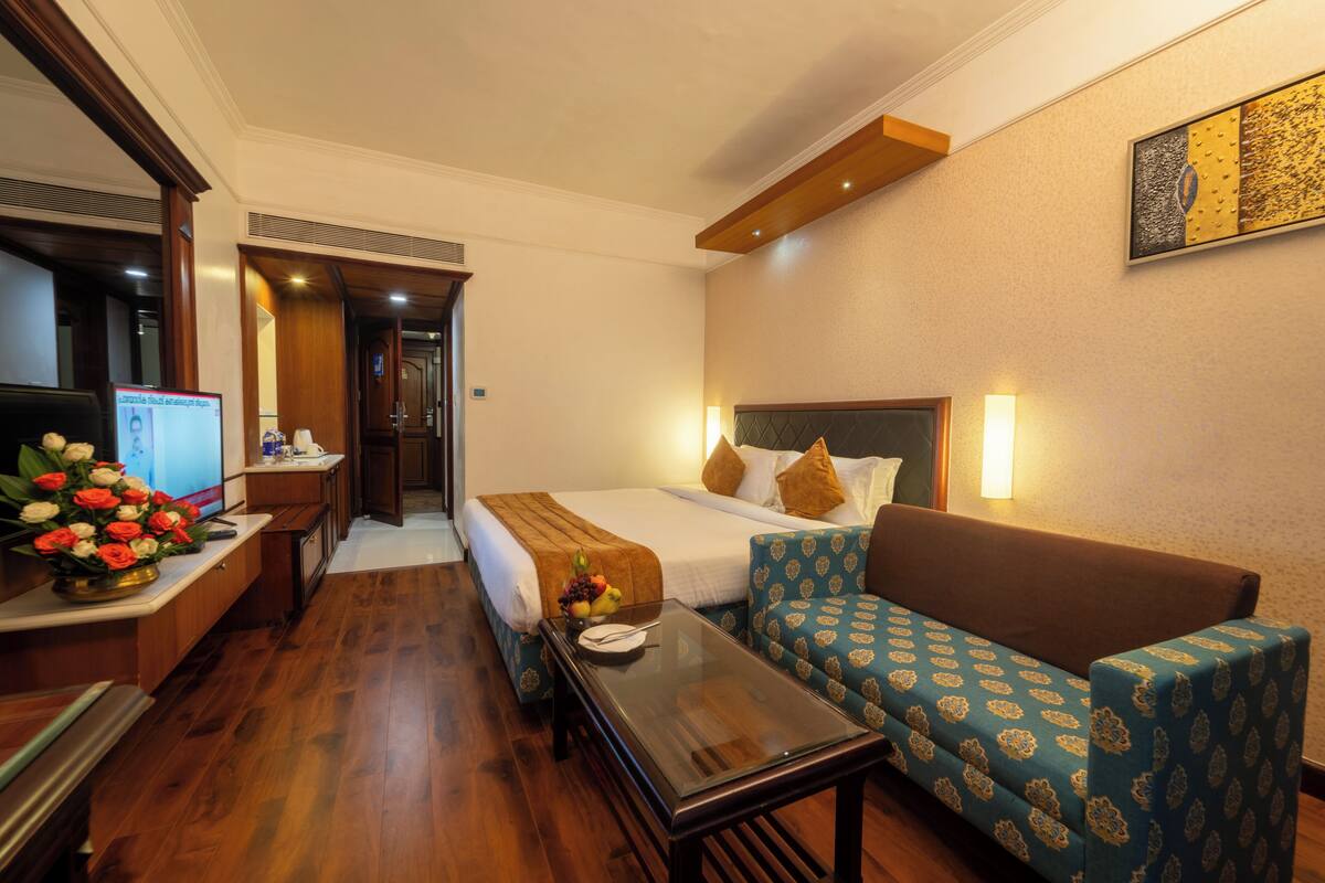 A hotel room with a bed, a sofa, a desk with a computer, and a coffee table.