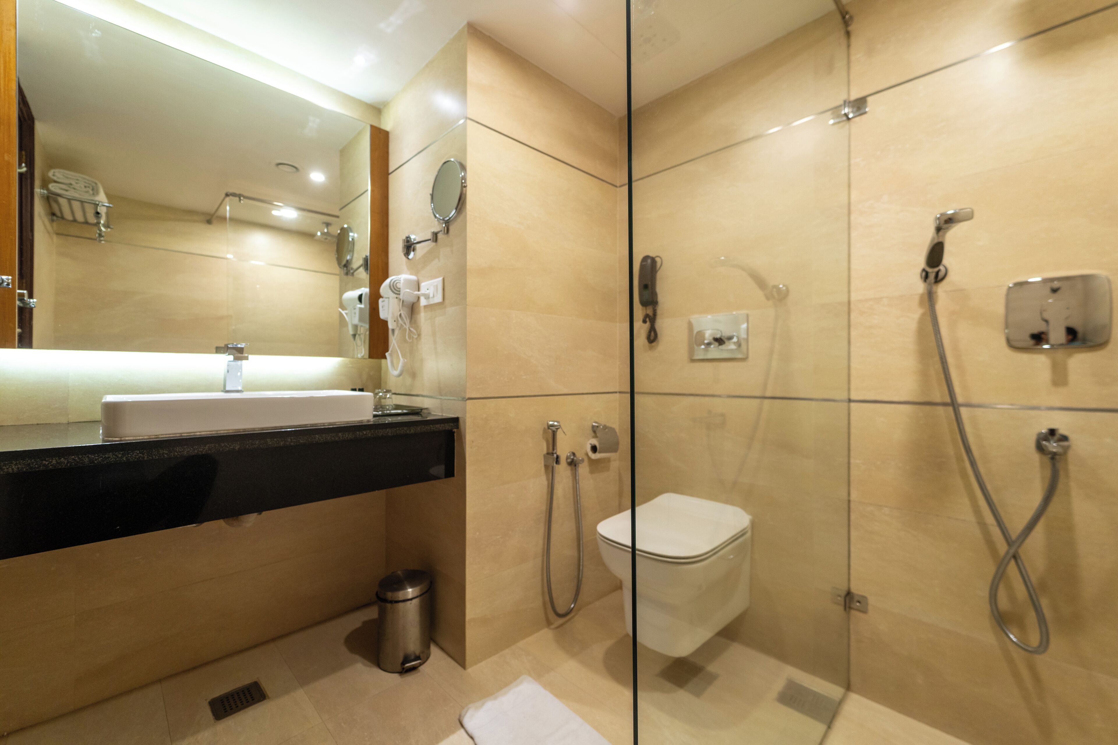 Un baño moderno con cabina de ducha de vidrio, inodoro y lavamanos con espejo superior.