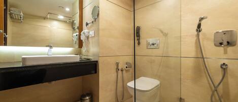 Un baño moderno con cabina de ducha de vidrio, inodoro y lavamanos con espejo superior.