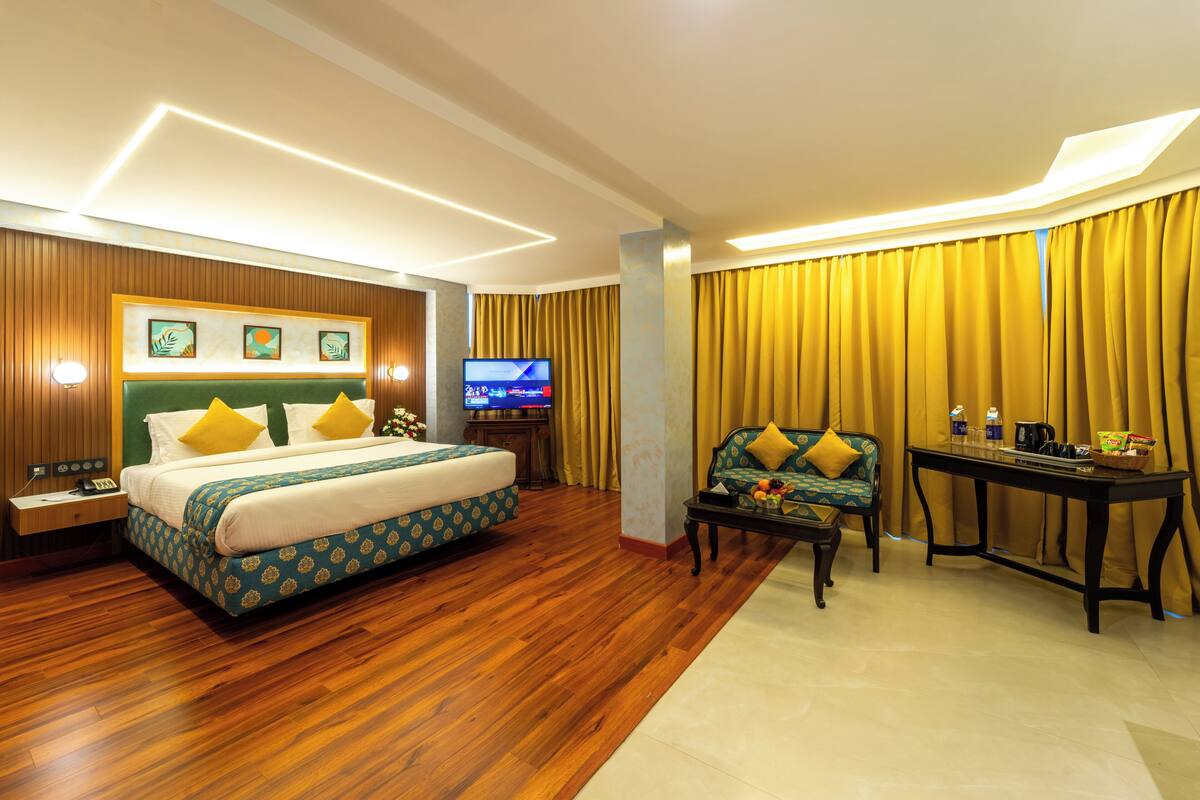 A hotel room with a bed, a sofa, a TV, and a table with items on it.