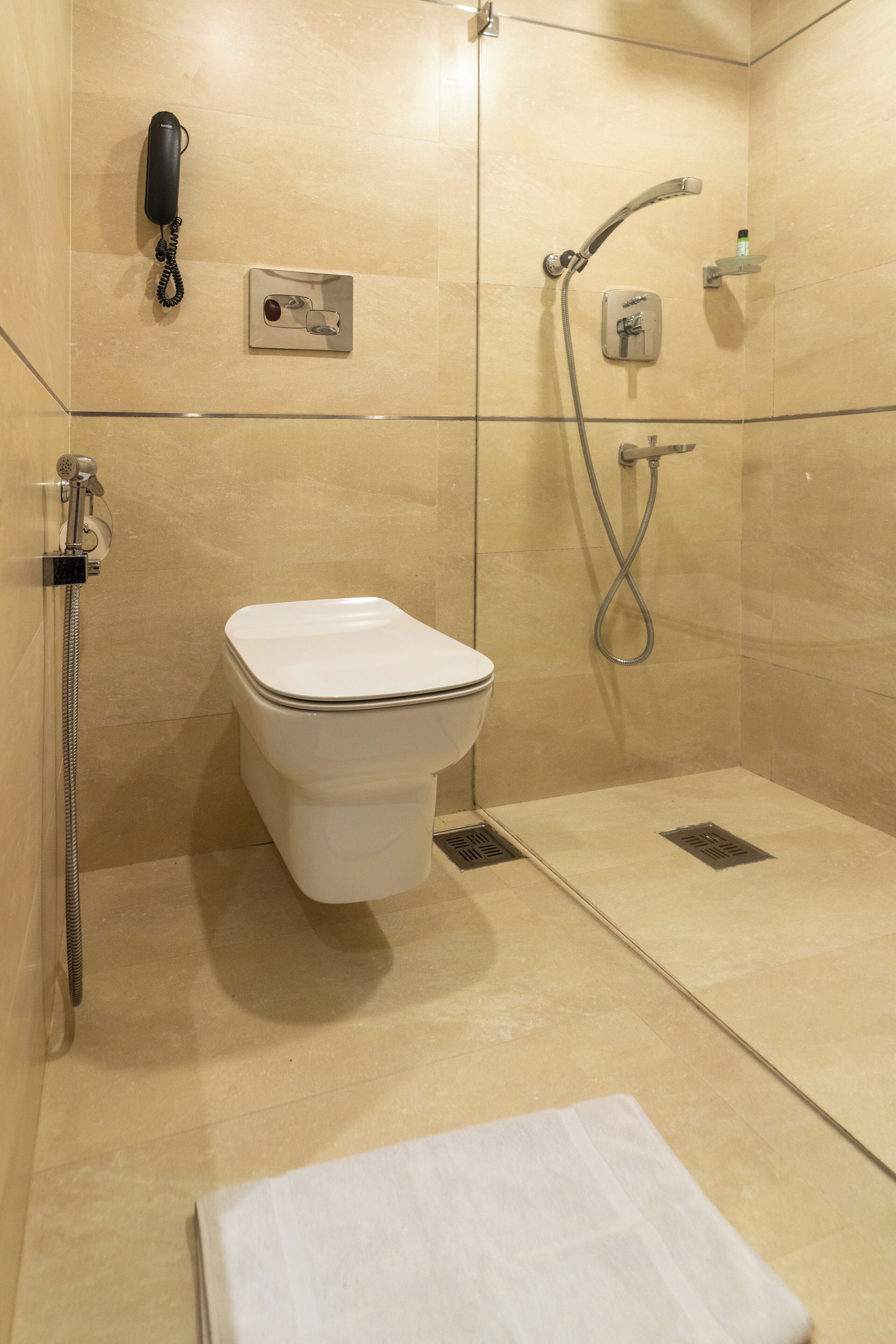 Un bagno moderno con un water, una doccia e un telefono fissato alla parete.