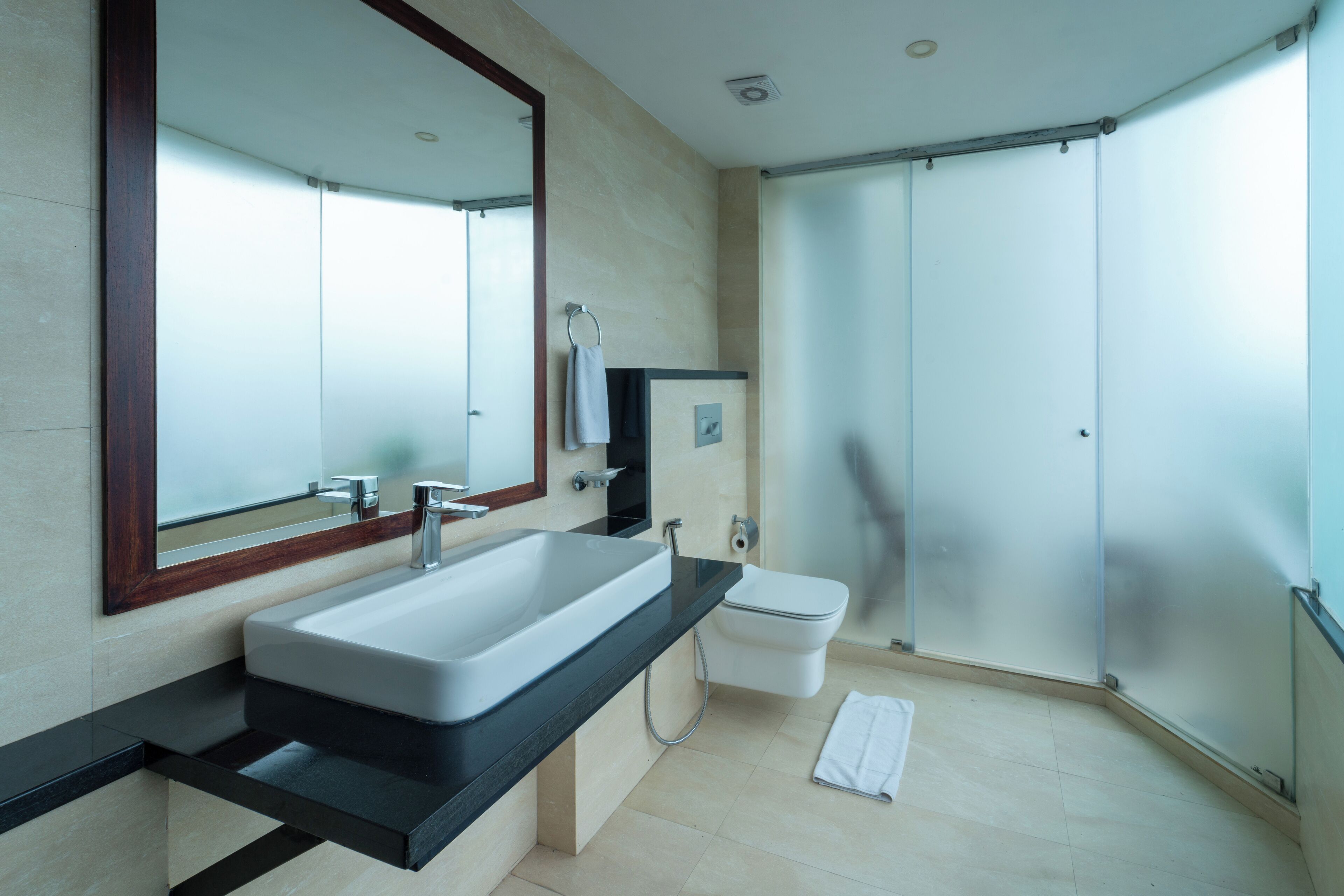 Un baño moderno con un espejo grande, un lavabo, un inodoro y una zona de ducha.