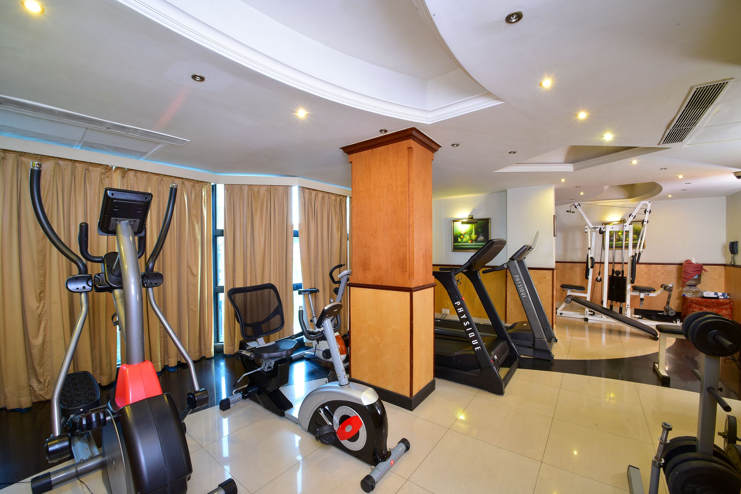 Une salle de sport équipée de machines de cardio, d’un tapis de course et de machines de musculation.