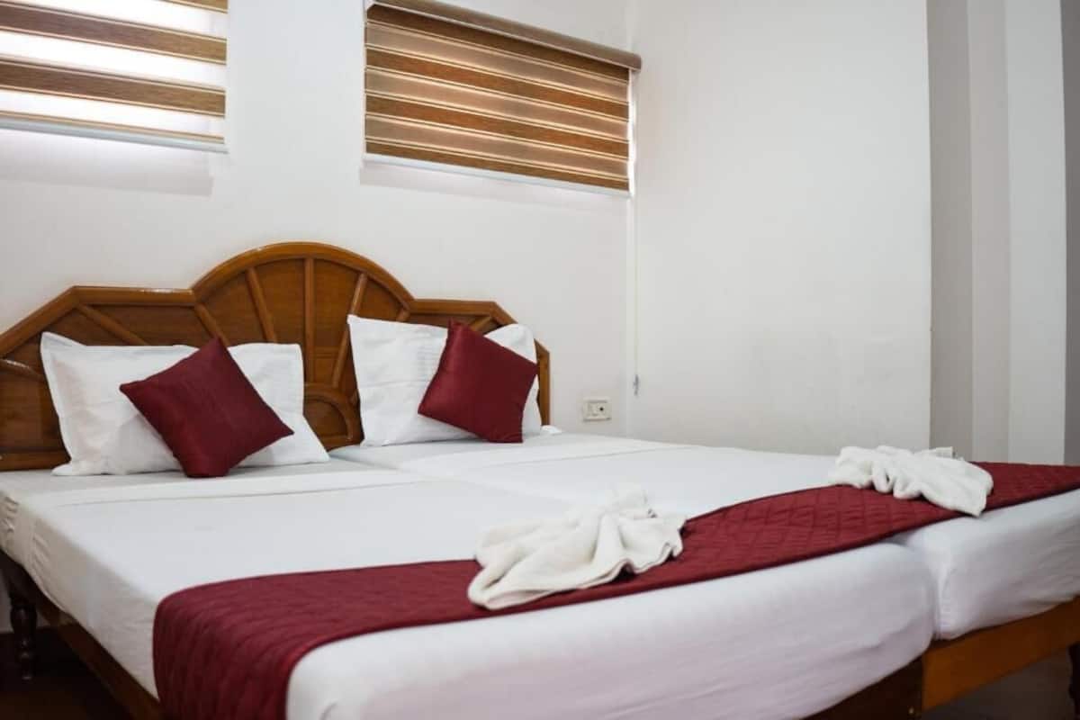 A double bed with wooden headboard, white and red pillows, and a red blanket.