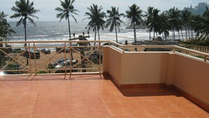 A terrace with a view of the ocean and palm trees, featuring tiled flooring and a railing. - Hotel Marine Palace (Neyyattinkara)