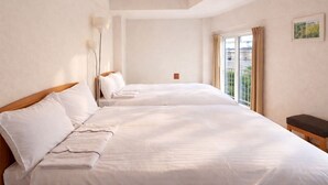 A hotel room with a large bed, a bedside table, a lamp, and a window with curtains. - Sakura Hotel Hatagaya (Tokyo)