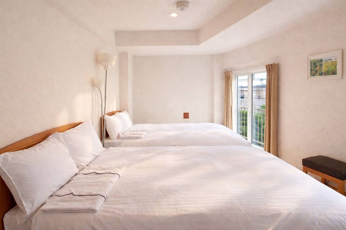 A hotel room with a large bed, a bedside table, a lamp, and a window with curtains.