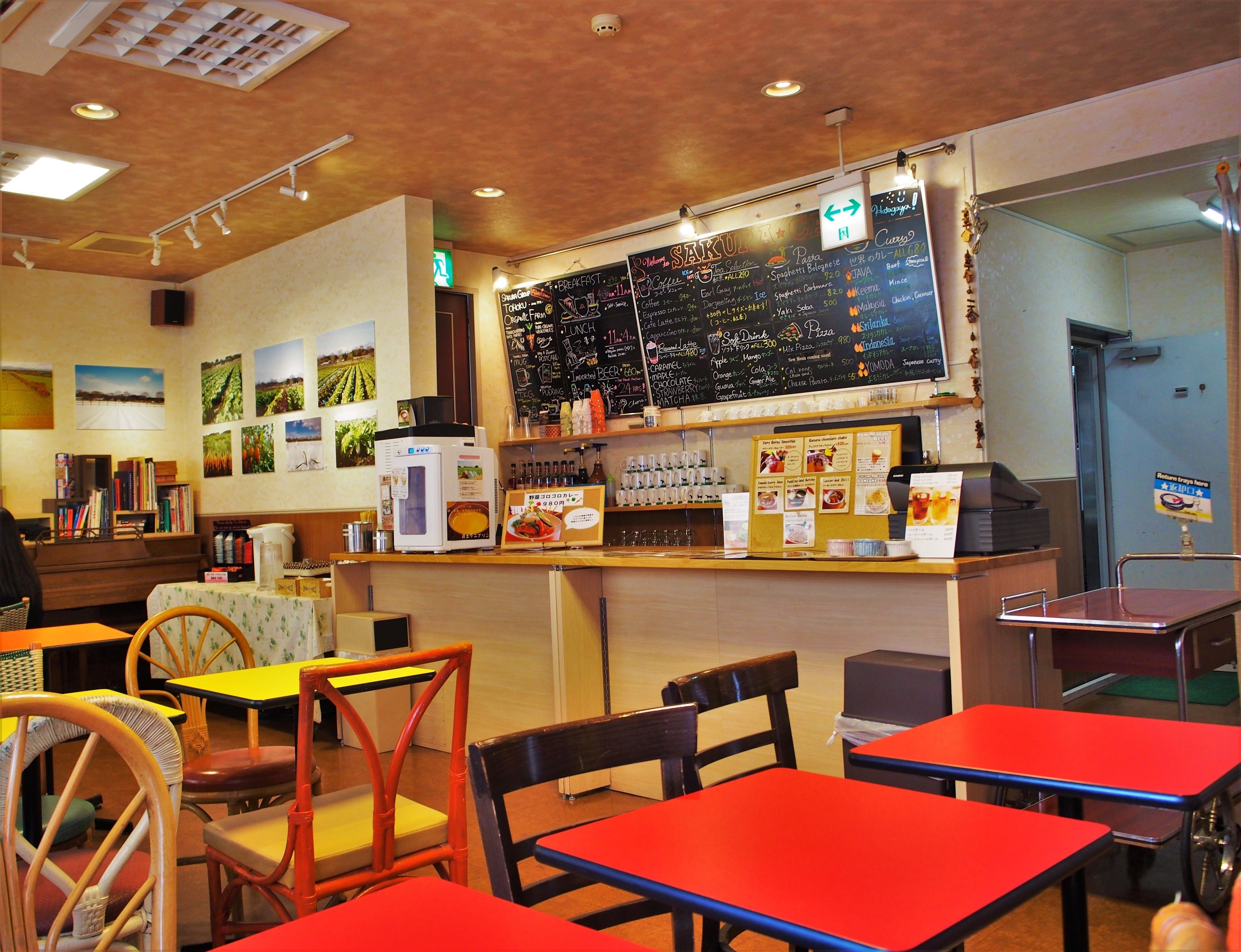 A restaurant interior with a chalkboard menu, tables, chairs, and a refrigerator.
