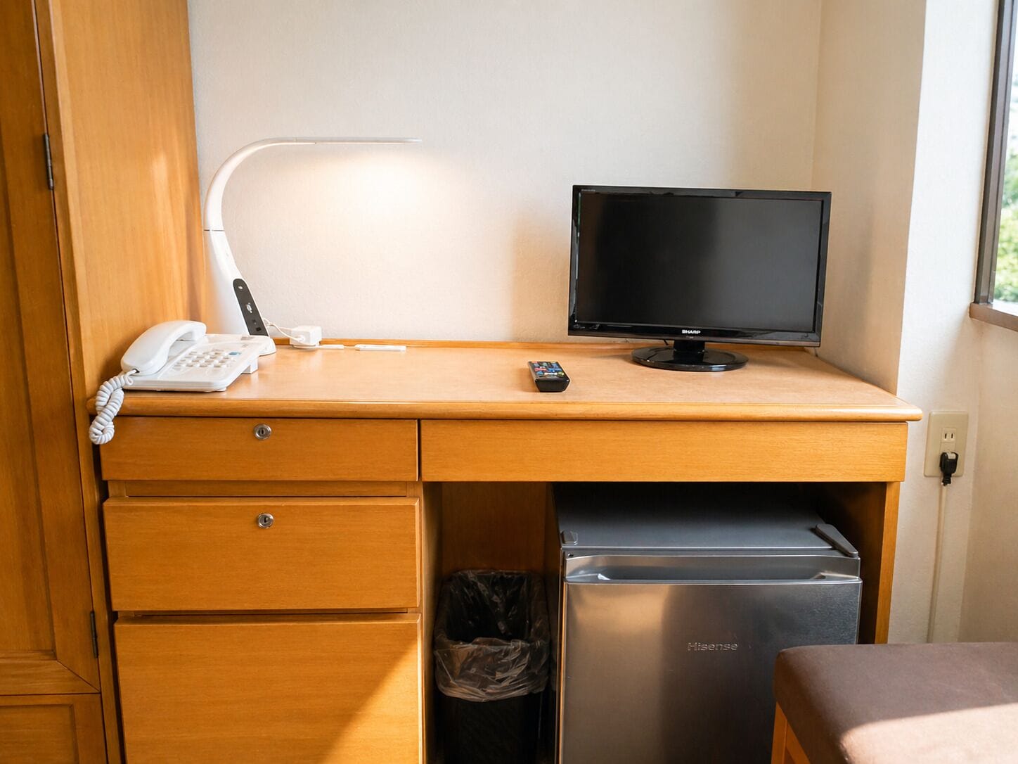 Ein Holztisch mit Telefon, Fernbedienung und Monitor.