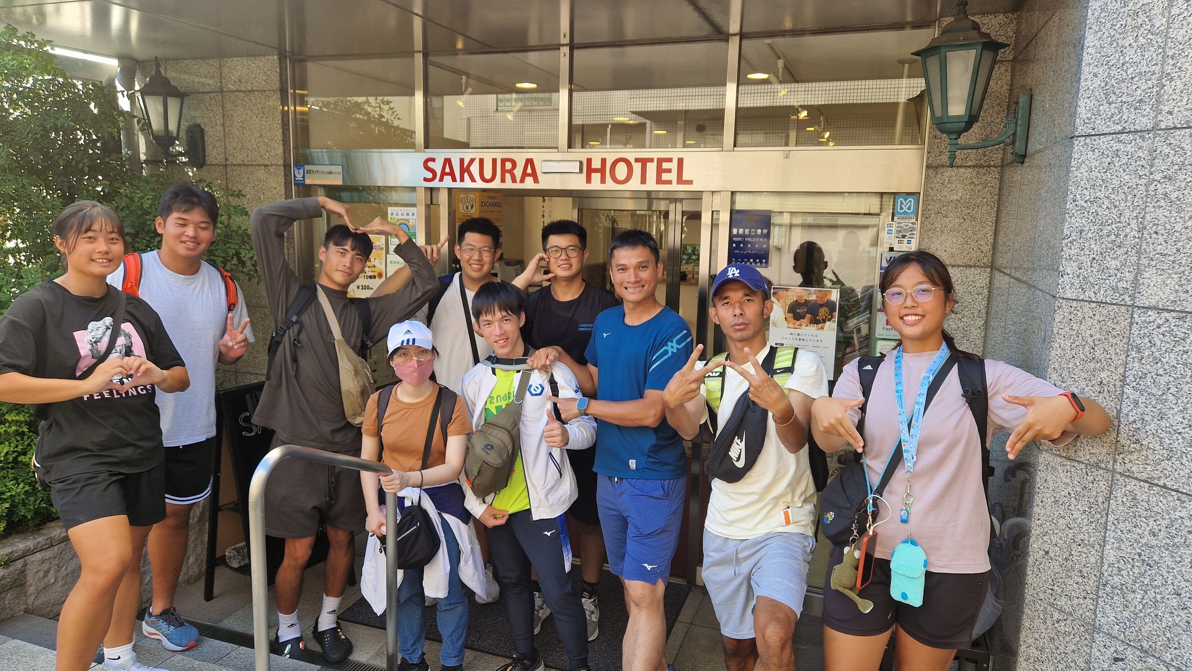 A group of people posing in front of the Sakura Hotel.