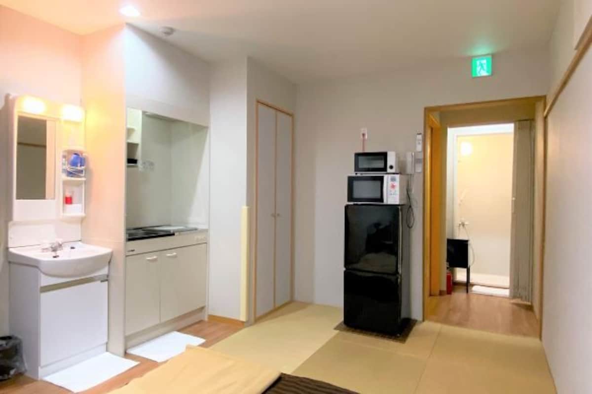 A hotel room with a kitchenette, a sink, a microwave, and a small refrigerator.