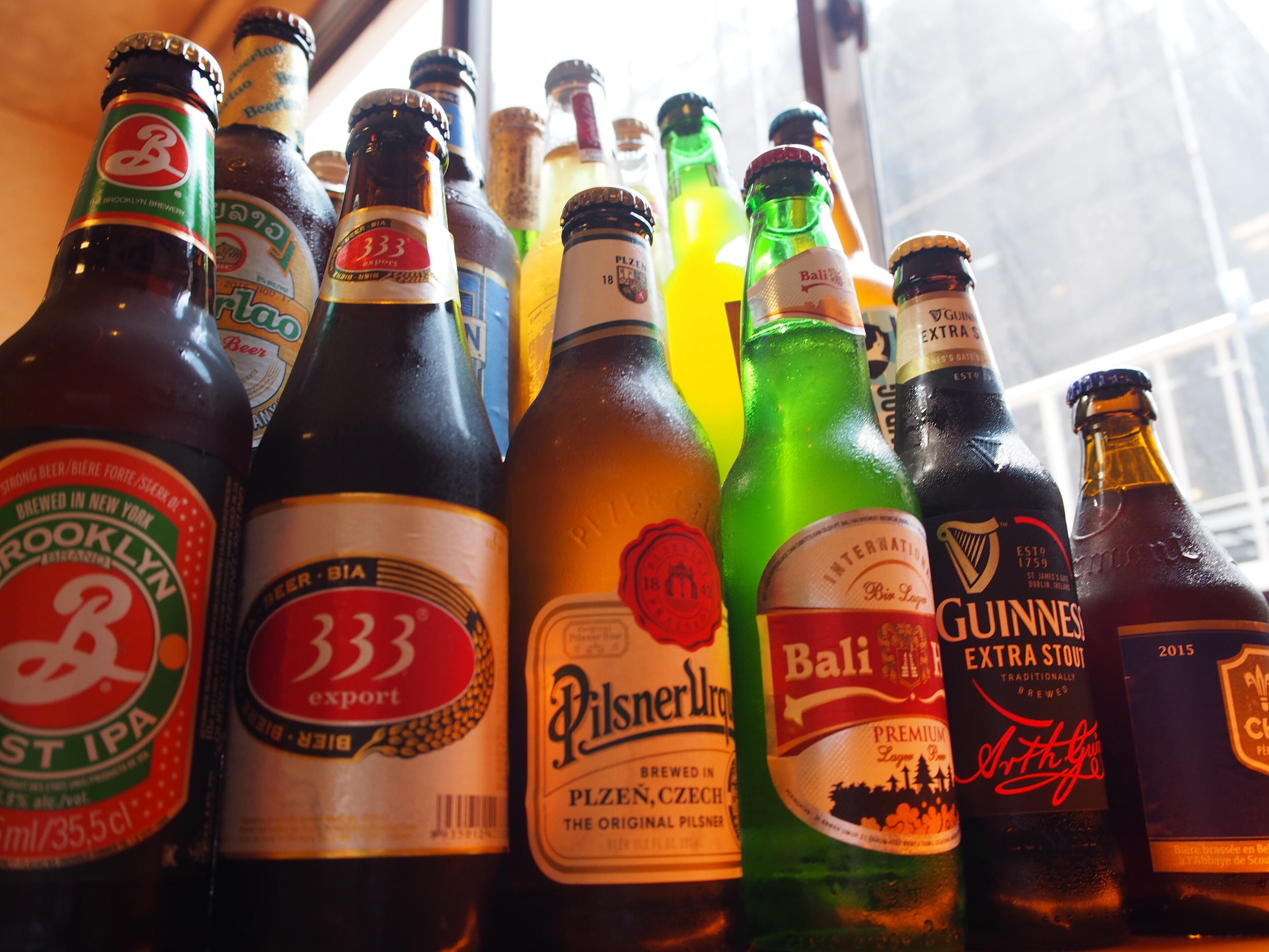 A variety of beer bottles arranged closely together.