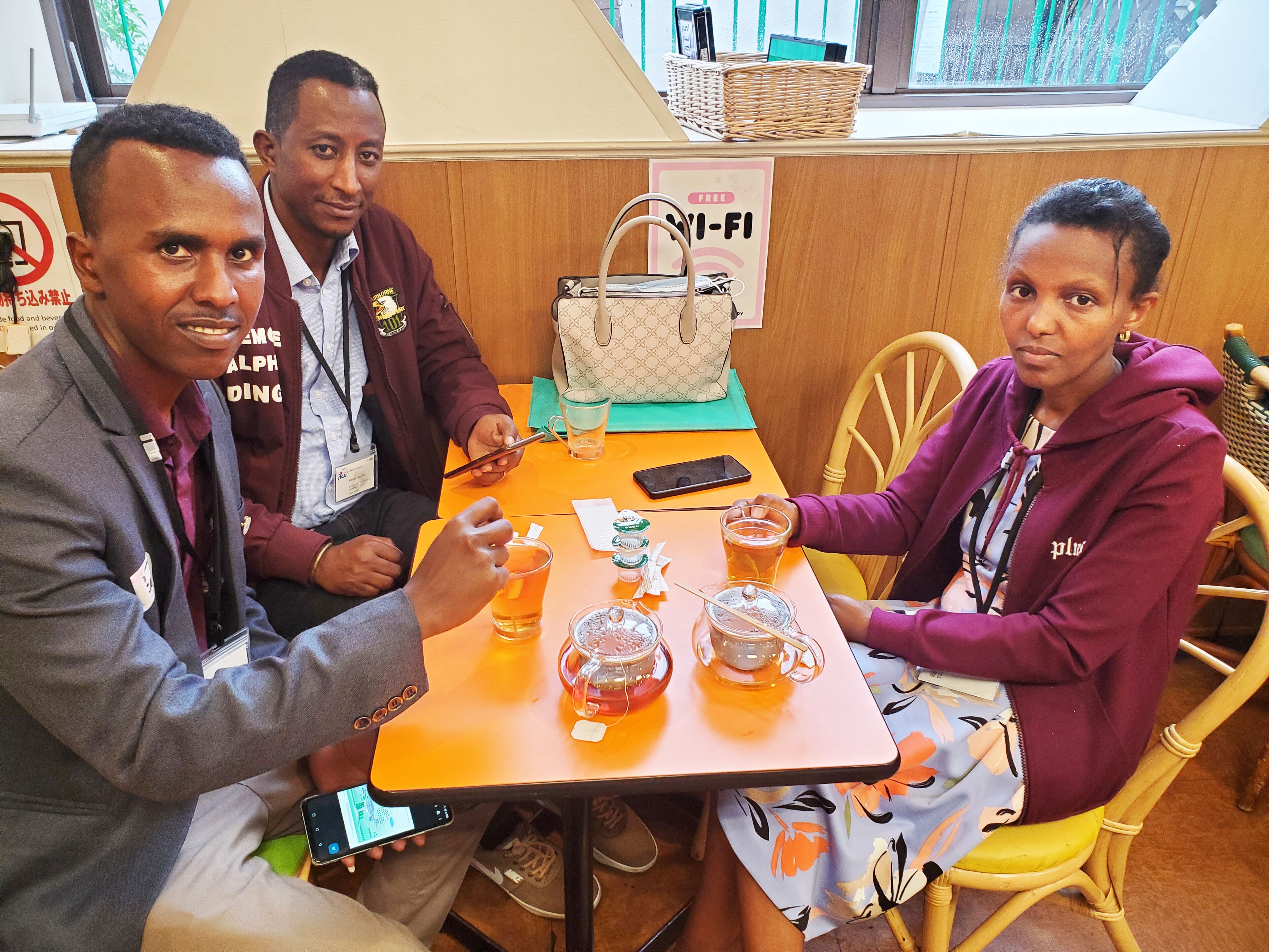 A group of people seated at a table with a sign indicating free Wi-Fi.