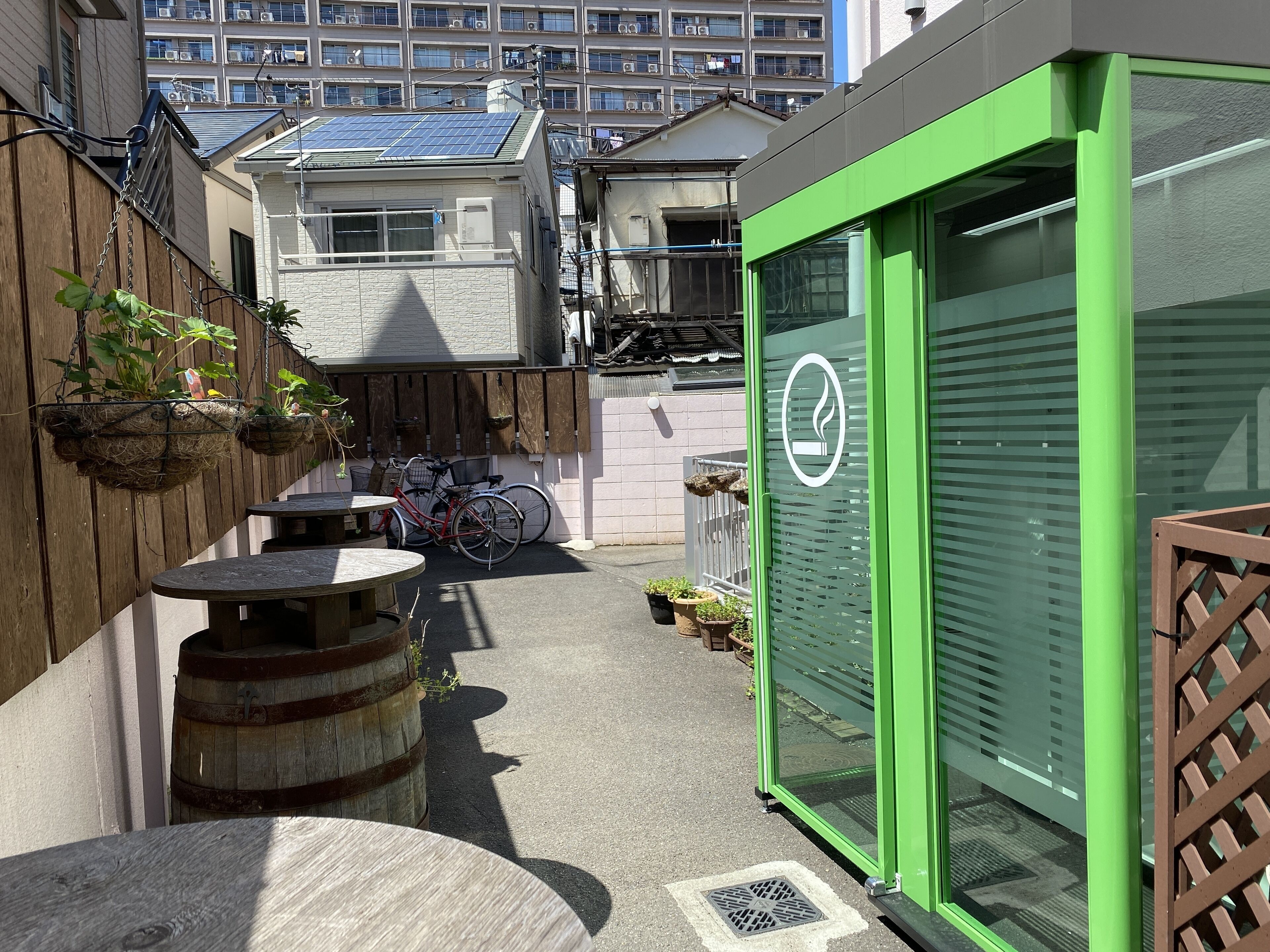 Un patio con una puerta verde, una bicicleta y plantas colgantes.