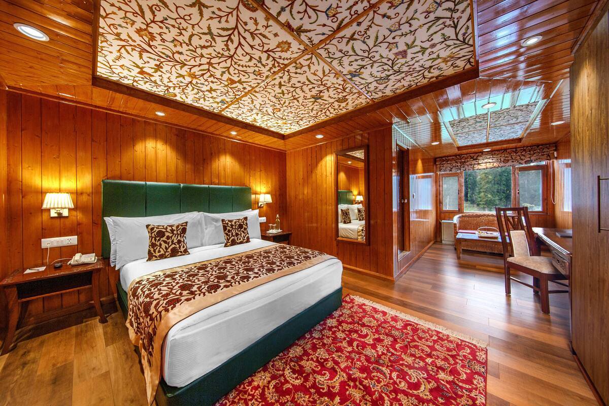 A spacious bedroom with a large bed, wooden walls, and a patterned ceiling.