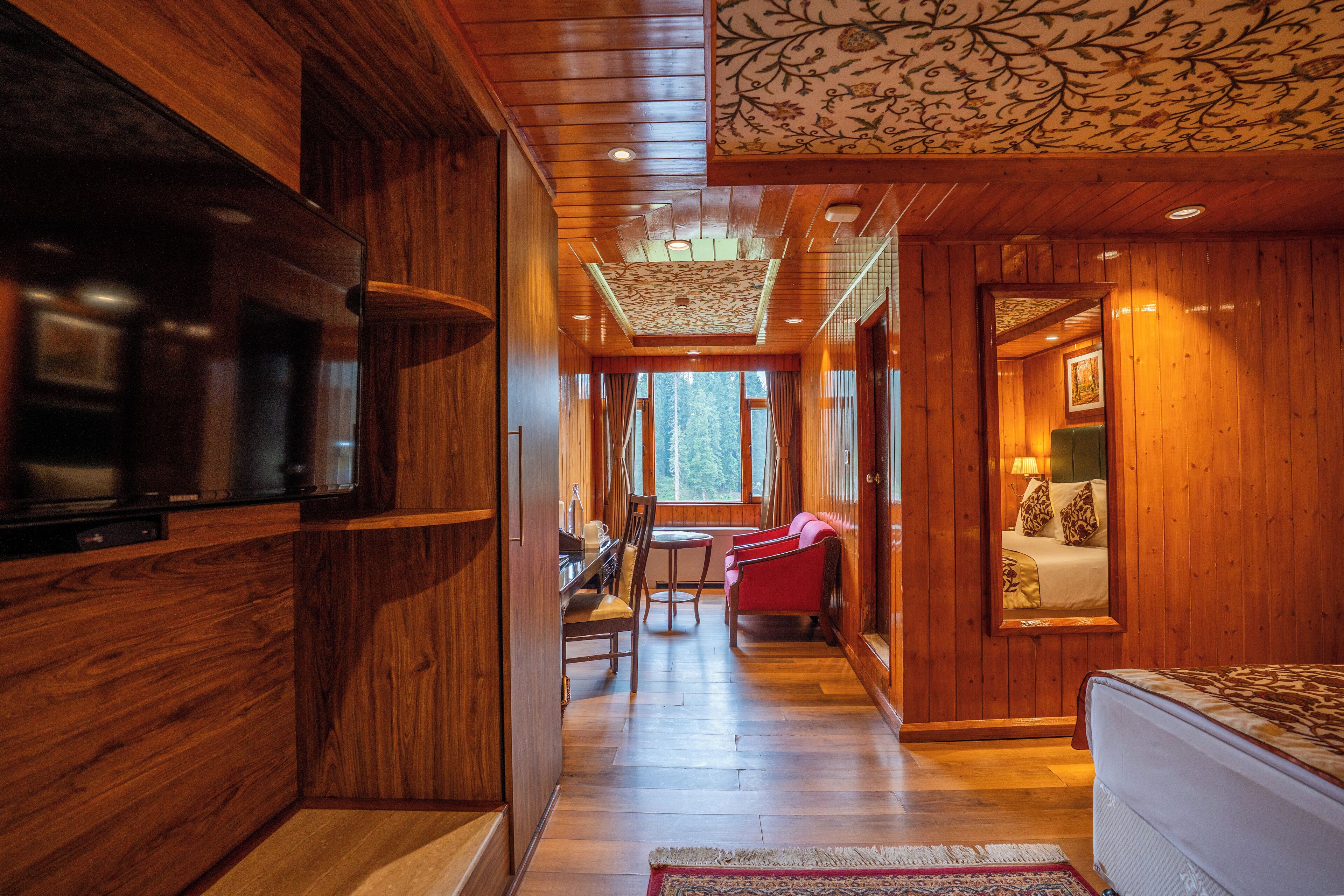 Un interior de madera con televisor, comedor y dormitorio con cama y ventana.