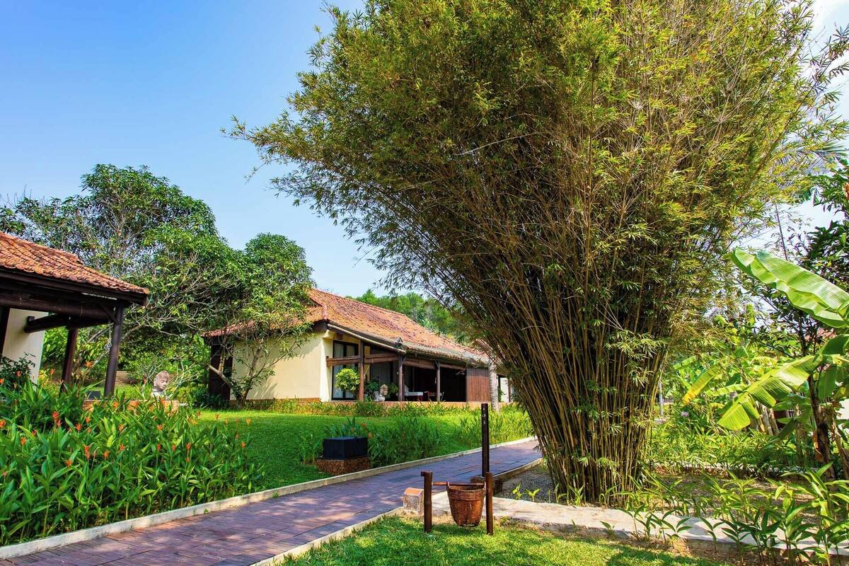 A traditional house with a tiled roof, surrounded by lush greenery and a well-maintained garden.