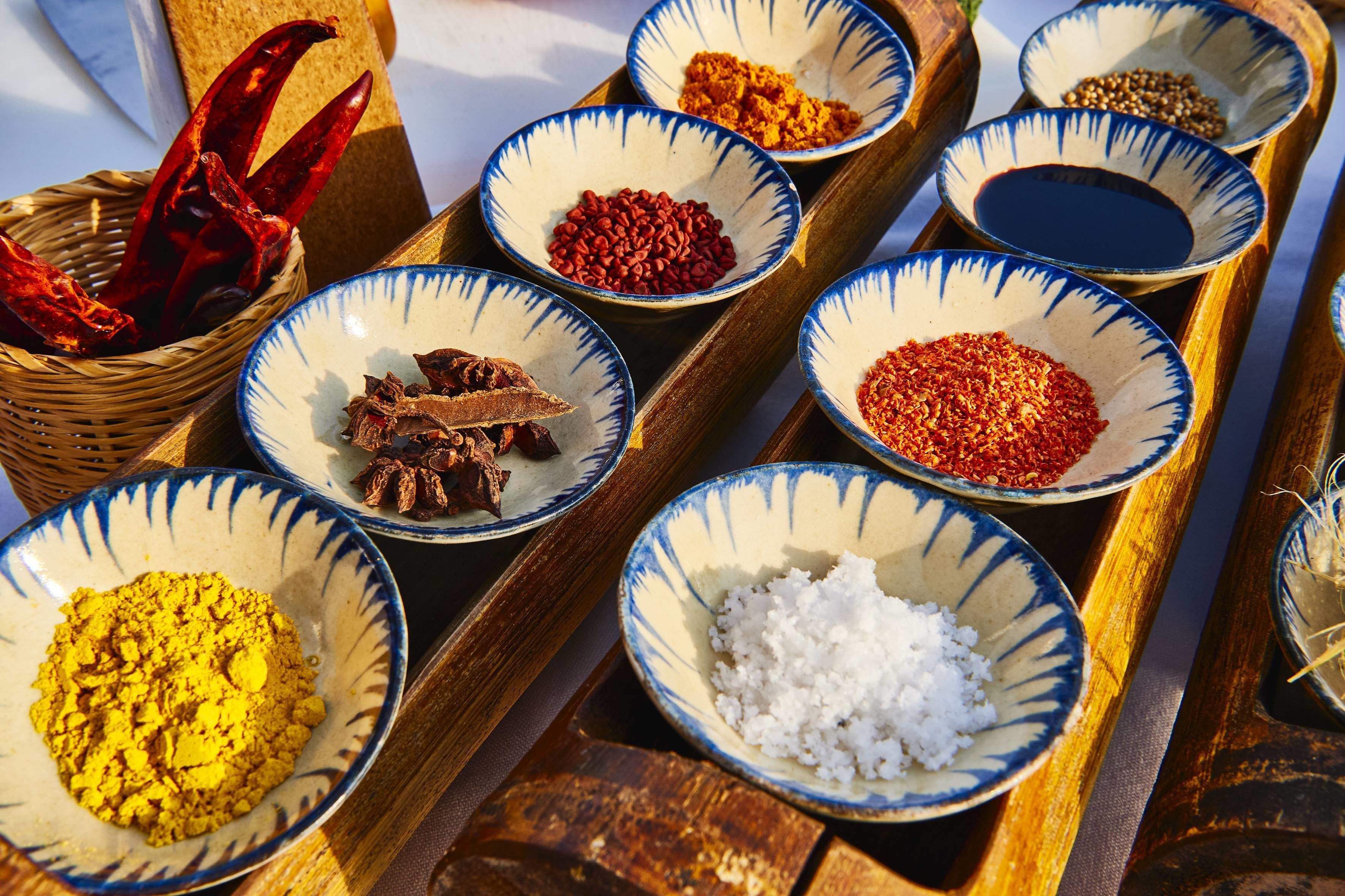 A tray with various bowls containing spices and dried chilies.