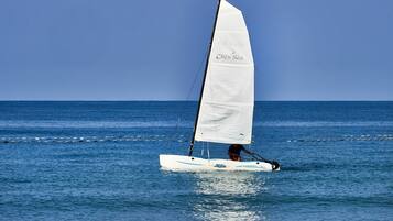 A sailboat with a white sail on the water.