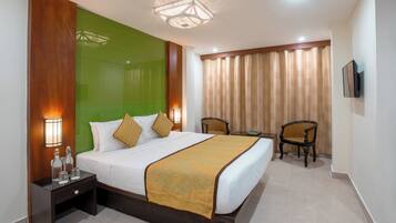 A hotel room with a bed, bedside table, lamps, a chair, a television, and a curtain.