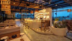 A modern bar area with seating, a counter, and a view of the outdoors. - TSG EMERALD VIEW HOTEL AND SPA (Port Blair)