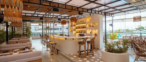 Uma área de bar moderna com assentos, balcão e vista para o exterior.