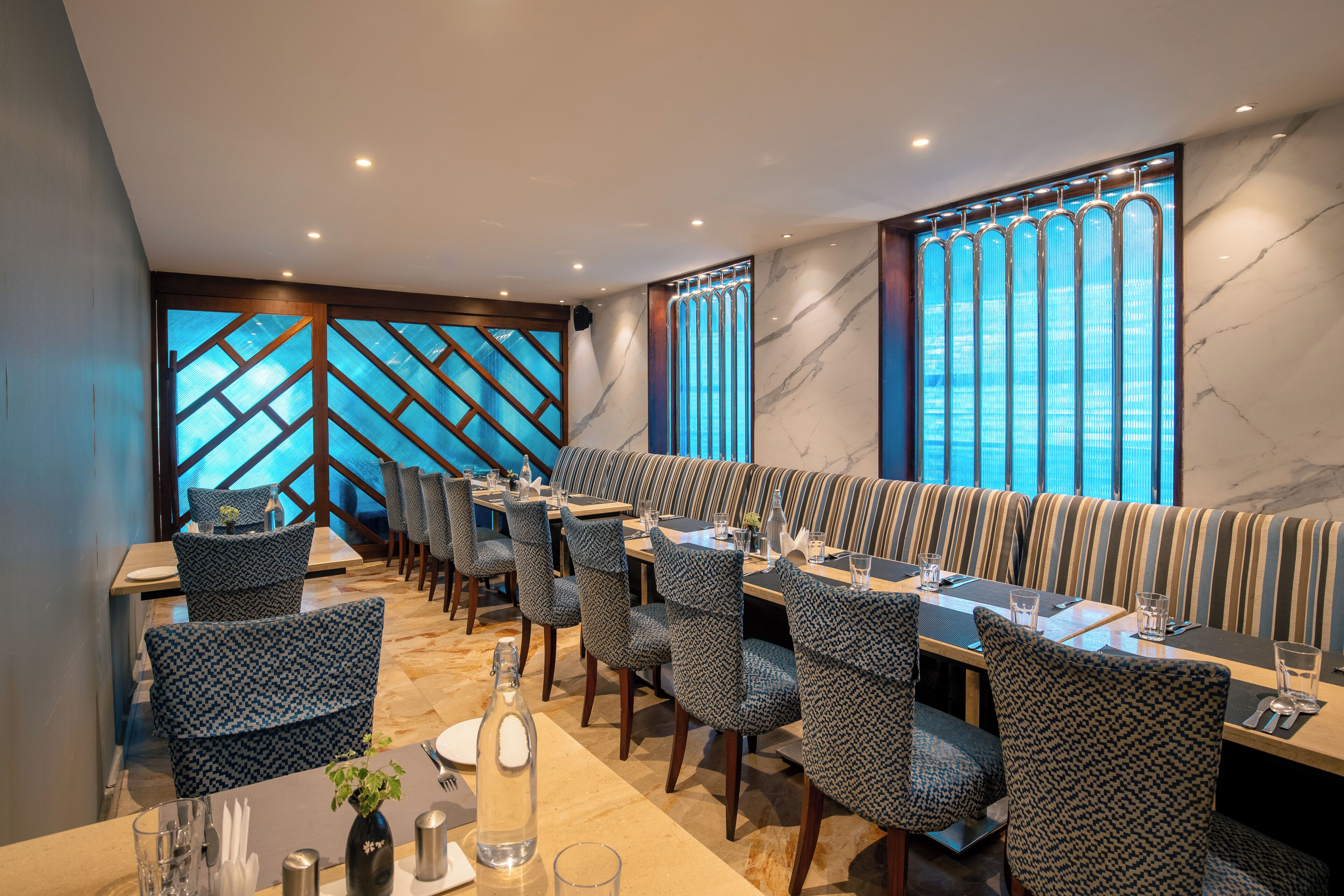 A restaurant with a long counter, patterned chairs, and a view through large windows.