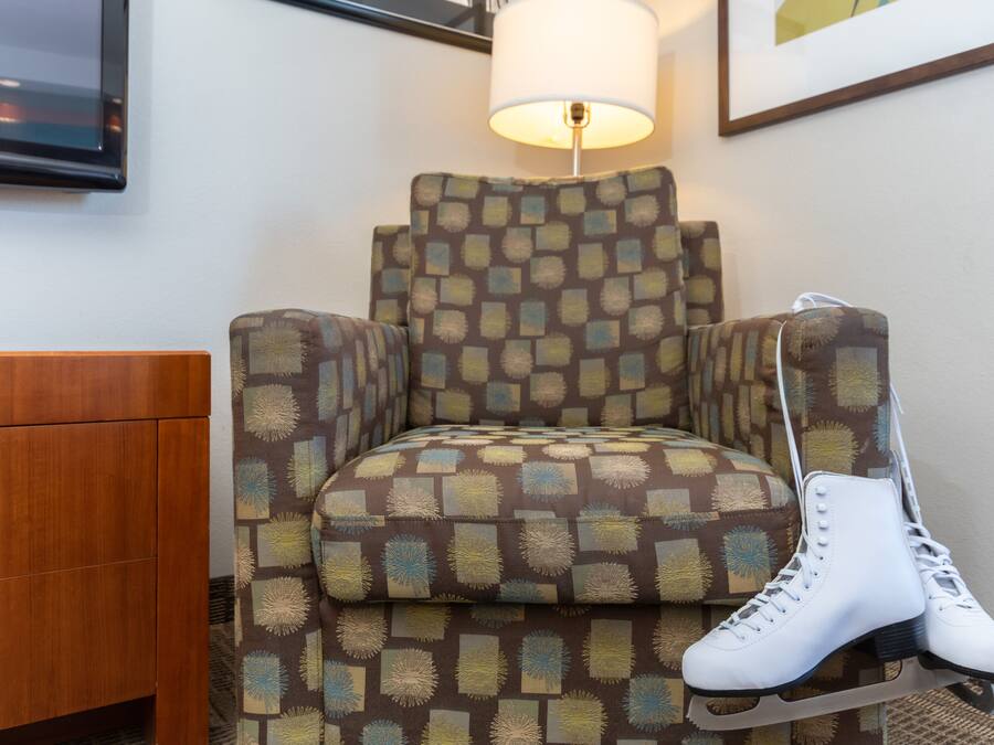 A chair with a patterned fabric and a pair of white roller skates placed on it.