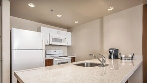 Una cocina moderna con electrodomésticos blancos, una encimera de granito y un fregadero de acero inoxidable.
