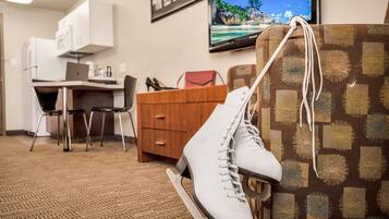 A hotel room with a desk, laptop, and a TV displaying a tropical beach scene.