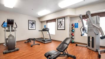 Une salle de sport équipée de matériel d’exercice, d’un tapis de course et d’un banc.