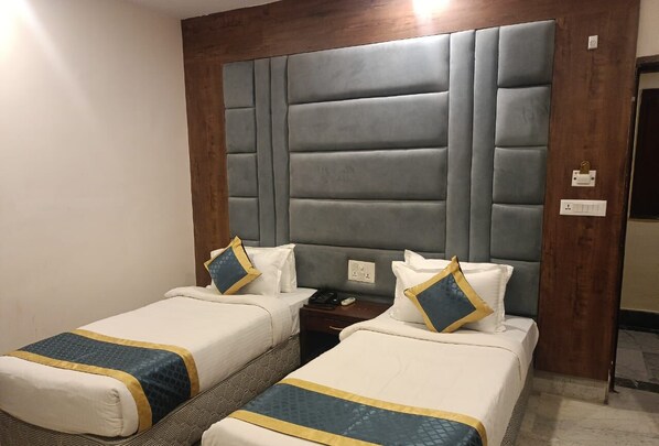 A hotel room with two beds, a wooden headboard, and a nightstand with a phone. - Hotel Taj Darbar (Gaya)