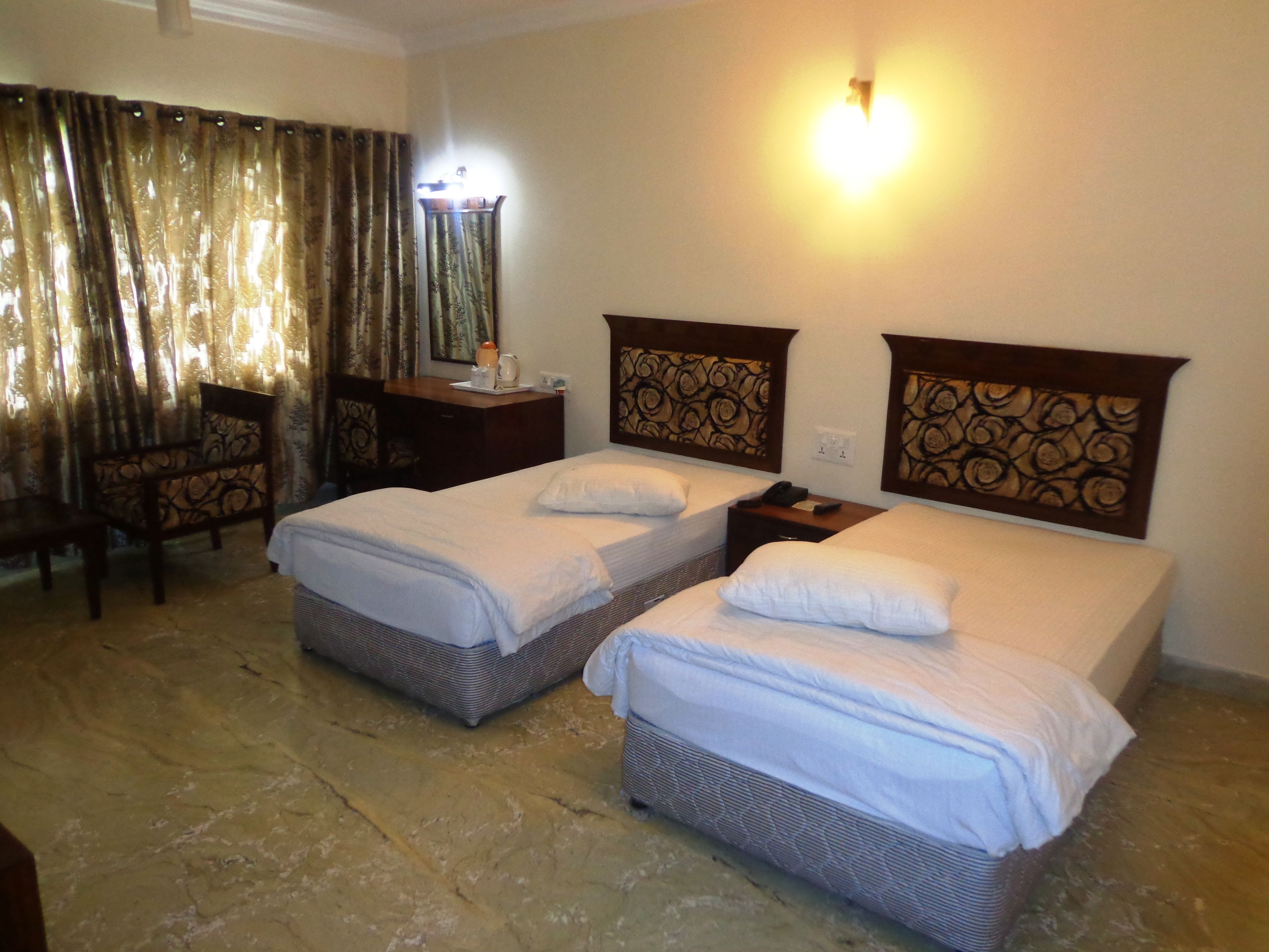A hotel room with two beds, a desk, a chair, and a mirror.