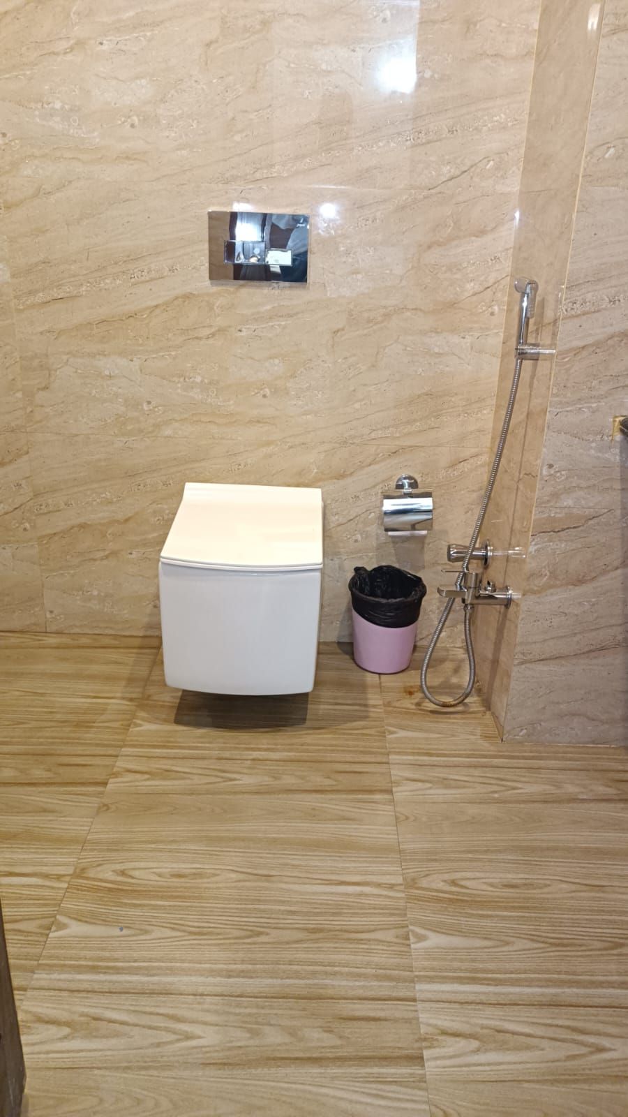Un baño con inodoro blanco, ducha y un cubo de basura.