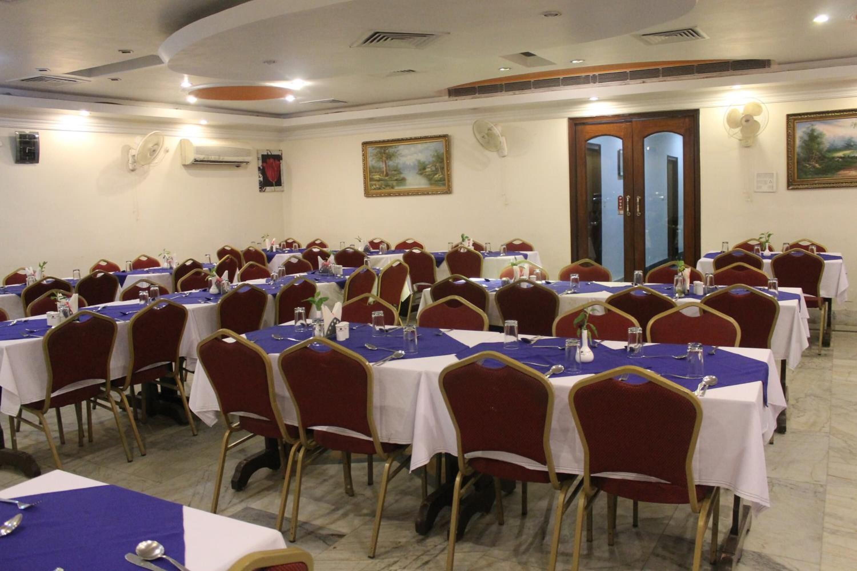Sala de conferências com várias mesas e cadeiras, dispostas em fileiras.